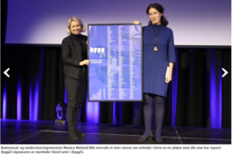 foto fra en bygg 21 konferanse med to kvinner som står på en scene og holder en plakat