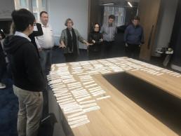 en gruppe mennesker som står rundt et bord med papirer